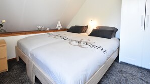 A bedroom with a bed, a nightstand, a dresser, and a small table with decorative items. - Cozy Holiday Home in Zonnemaire Near Lakebeach (Zonnemaire)