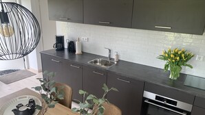 Eine moderne Küche mit dunklen Schränken, einer Edelstahlspüle und einem eingebauten Backofen.