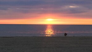 A beach at sunset with a person standing in the distance. - Holiday Home in Egmond aan zee With Fenced Garden (Egmond aan Zee)