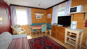 A cozy living room with a sofa, a dining table, and a television. - Cozy Apartment in Feld am See Near Ski Slopes (Feld am See)