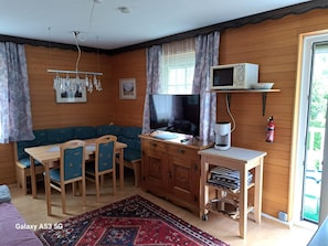 A cozy room with a wooden interior, a television, a desk with a computer, a dining table with chairs, and a patterned rug. - Cozy Apartment in Feld am See Near Ski Slopes (Feld am See)