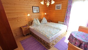 A wooden-paneled bedroom with a bed, bedside tables, a chandelier, and a window with curtains. - Cozy Apartment in Feld am See Near Ski Slopes (Feld am See)