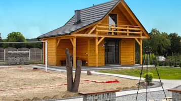 Una cabaña de madera con techo a dos aguas, un porche y una pared de piedra.