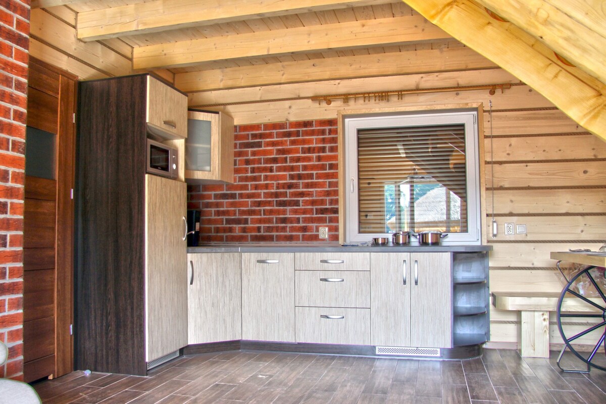 A kitchen with wooden cabinets, a brick wall, and a window with blinds.