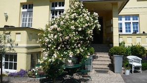 A yellow building with a balcony, a rose bush, and outdoor seating. - Relaxa at a Luxurious Villa in Bad Pyrmont (Bad Pyrmont)