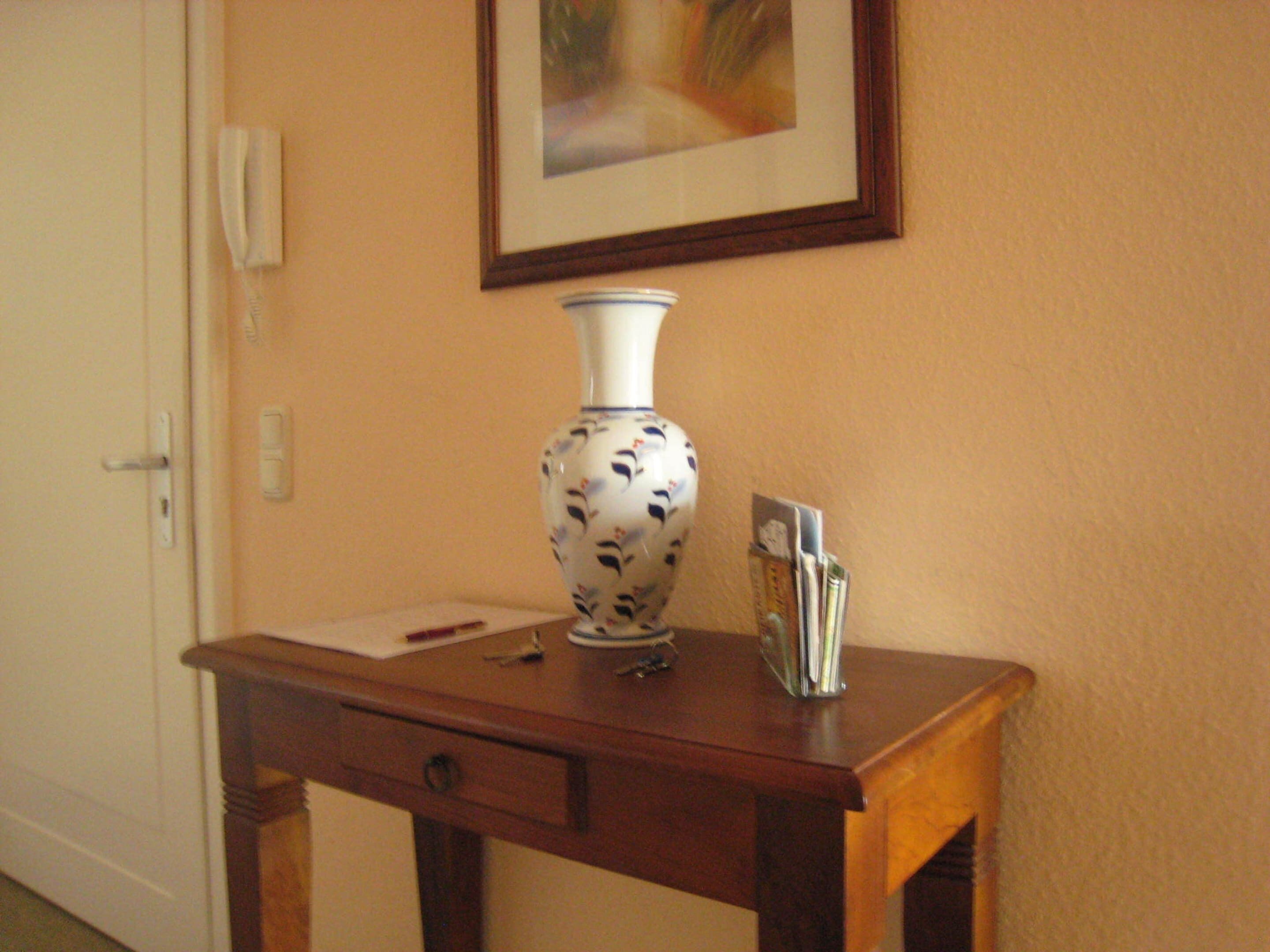 A wooden desk with a vase, a pen, and a card holder.