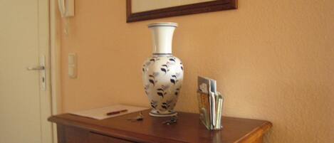 A wooden desk with a vase, a pen, and a card holder.