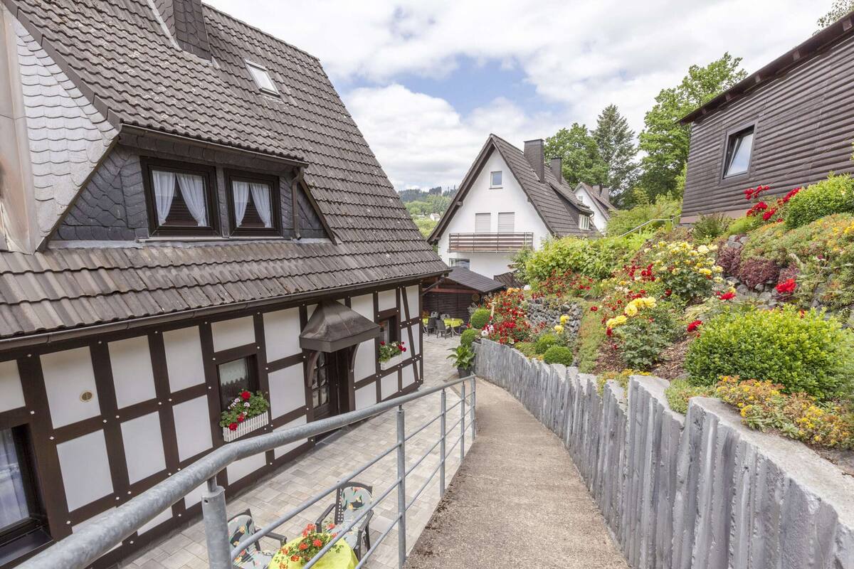 Une maison traditionnelle à colombages, dotée d’un balcon, d’un chemin de gravier et d’une clôture en bois.