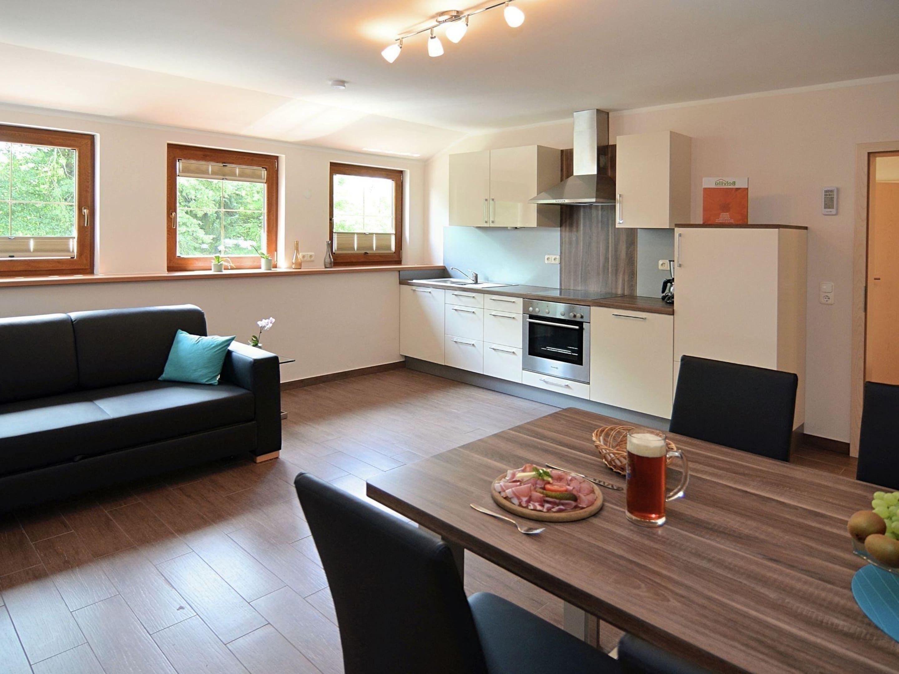Cocina moderna con comedor, que incluye un sofá, una mesa con comida y un ventanal grande.