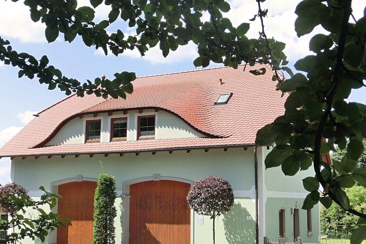 A two-story building with a red-tiled roof, wooden doors, and a small window.