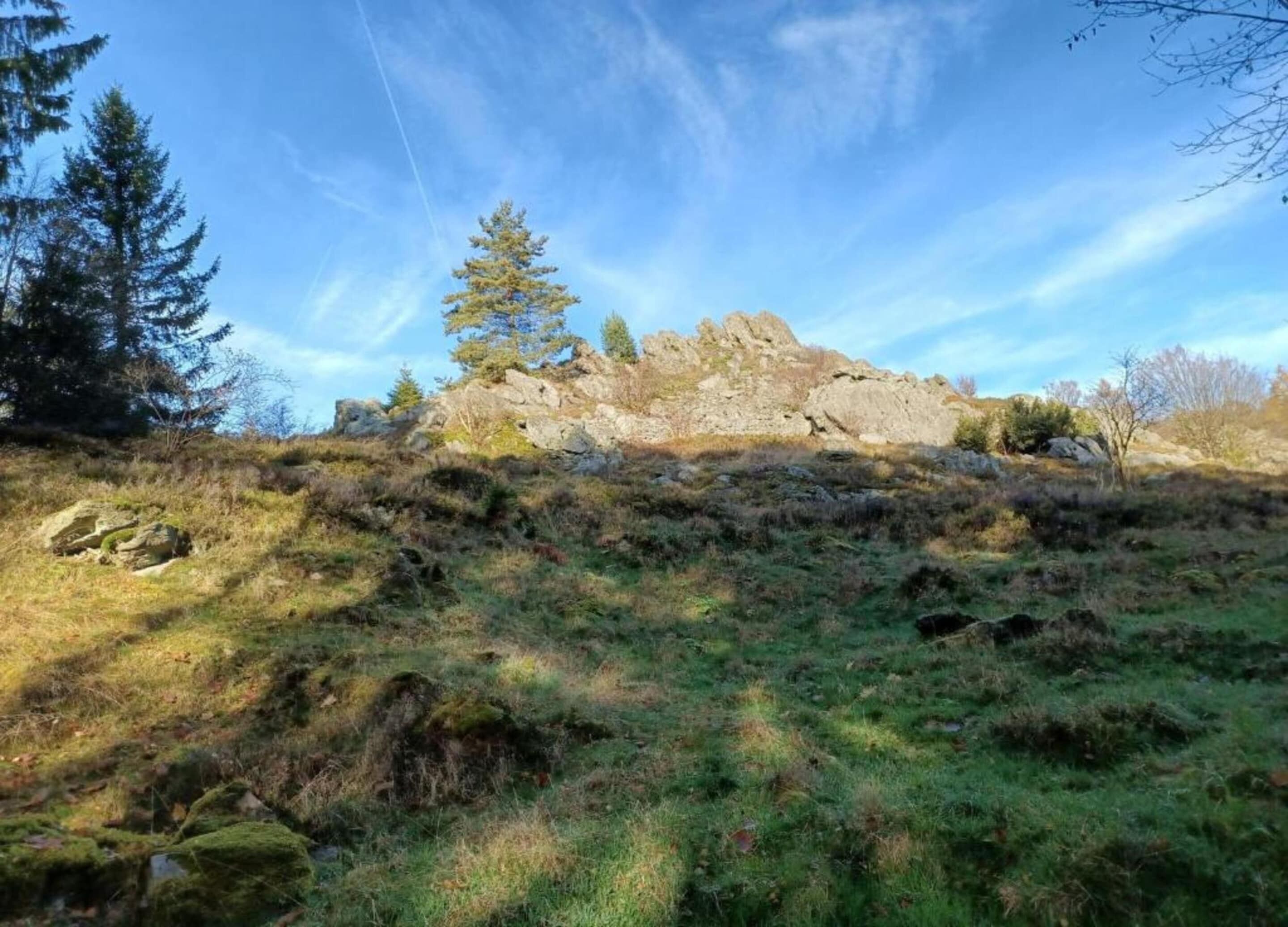 Une colline rocheuse à la végétation clairsemée, sous un ciel dégagé.