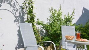 A patio with two metal chairs and a table, a basket, and a pitcher of beer. - Modern Apartment in Eslarn With Lake Near (Eslarn)