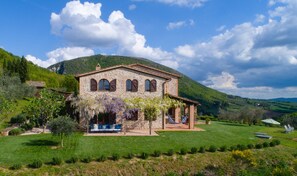 A stone house with a garden, a hammock, and a view of the hills.