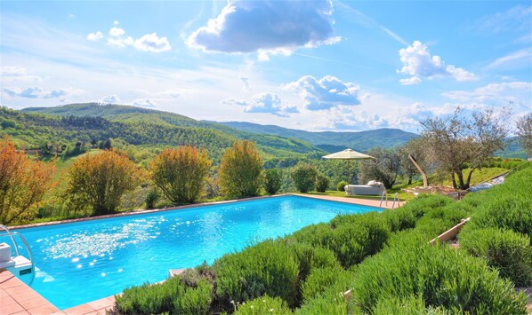 A swimming pool with a view of green hills and trees.