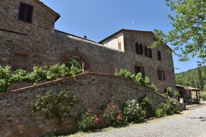 Ein Steinhaus mit Rundbogenfenstern und einem überdachten Außenbereich zum Sitzen.