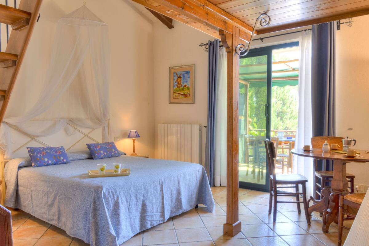 Une chambre à coucher avec un lit, une table et des chaises, une fenêtre et un radiateur.