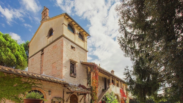 A rustic stone building with a tower, ivy-covered walls, and a gravel courtyard with a bench. - Farmhouse in Marsciano With Vineyards Olive Groves (Marsciano)