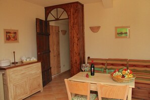 Ein Essbereich mit einem Holztisch, Stühlen, einer hölzernen Bank und einem an der Wand befestigten Obstkorb.