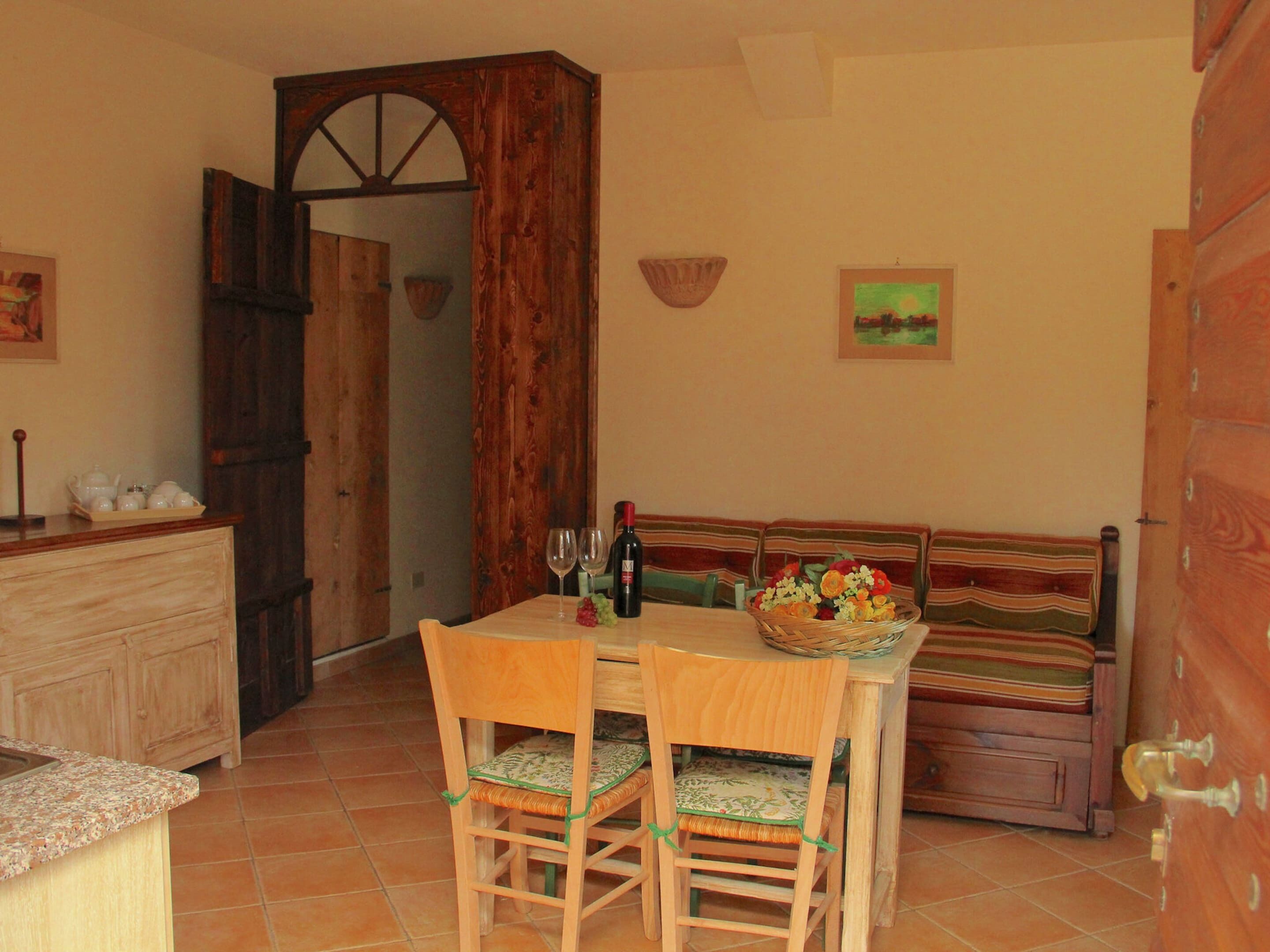 A dining area with a wooden table, two chairs, a bench, and a cabinet.