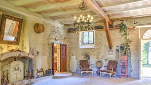 A rustic room with a stone fireplace, wooden chairs, a chandelier, and a brick floor. - Farmhouse in Marsciano With Vineyards Olive Groves (Marsciano)