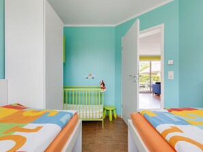 Ένα δωμάτιο με δύο κρεβάτια, μια κούνια και θέα σε έναν εξωτερικό χώρο.