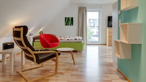 A modern living room with a wooden floor, a green sofa, a red chair, and a small table. - Pleasant Holiday Home in Zierow Near Sea (Zierow)