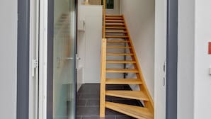 A wooden staircase leading to a landing with a white door and a glass door. - Pleasant Holiday Home in Zierow Near Sea (Zierow)