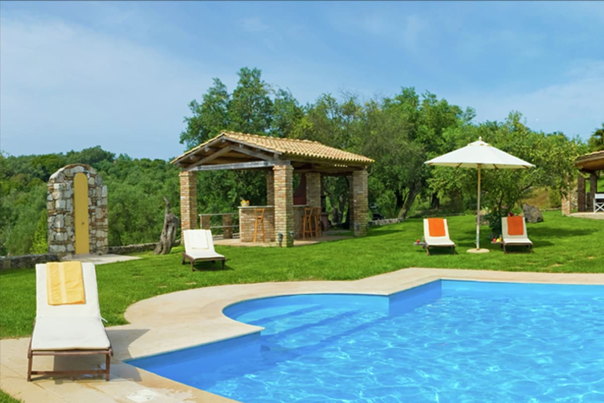 Une piscine avec des chaises longues et un kiosque.