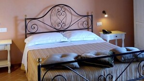 Ein Schlafzimmer mit einem Metallbettgestell, weißer Bettwäsche, einem Nachttisch mit Lampe und einer Steckdose.