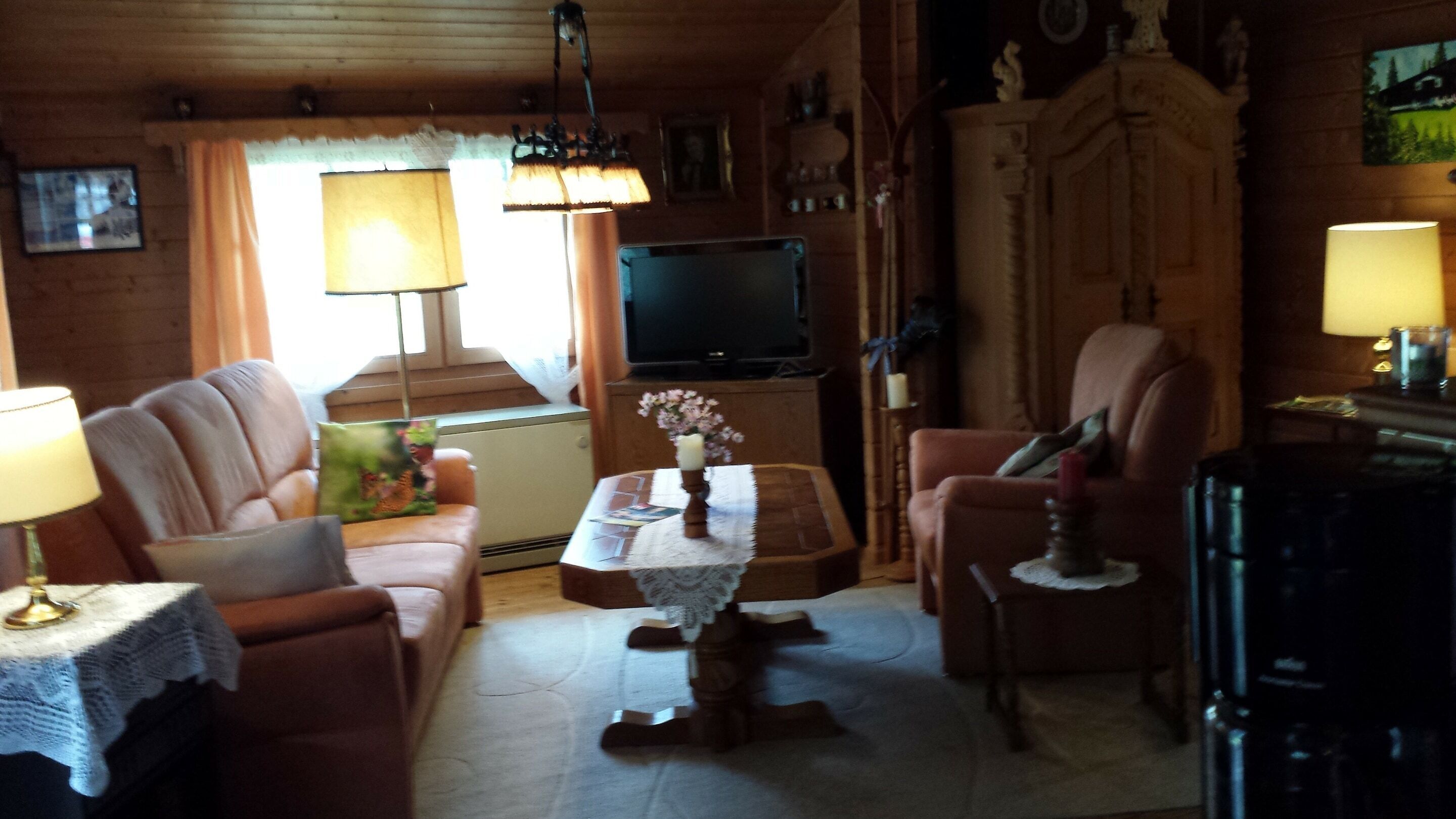 A cozy living room with a sofa, armchairs, a coffee table, and a television.