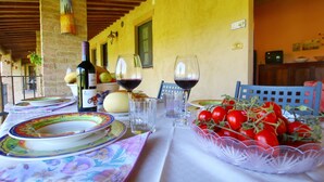 Une table dressée avec des assiettes, des verres, une bouteille de vin et un saladier de tomates.