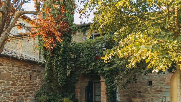 A stone building with a brick entrance, surrounded by greenery and a garden area. - Rustic Farmhouse in Cortona With Swimming Pool (Cortona)