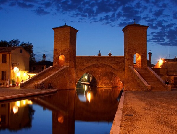 A stone bridge over a calm water body with a reflection, surrounded by buildings and a clear sky. - Characteristic Apartment in Codigoro With Pool (Codigoro)