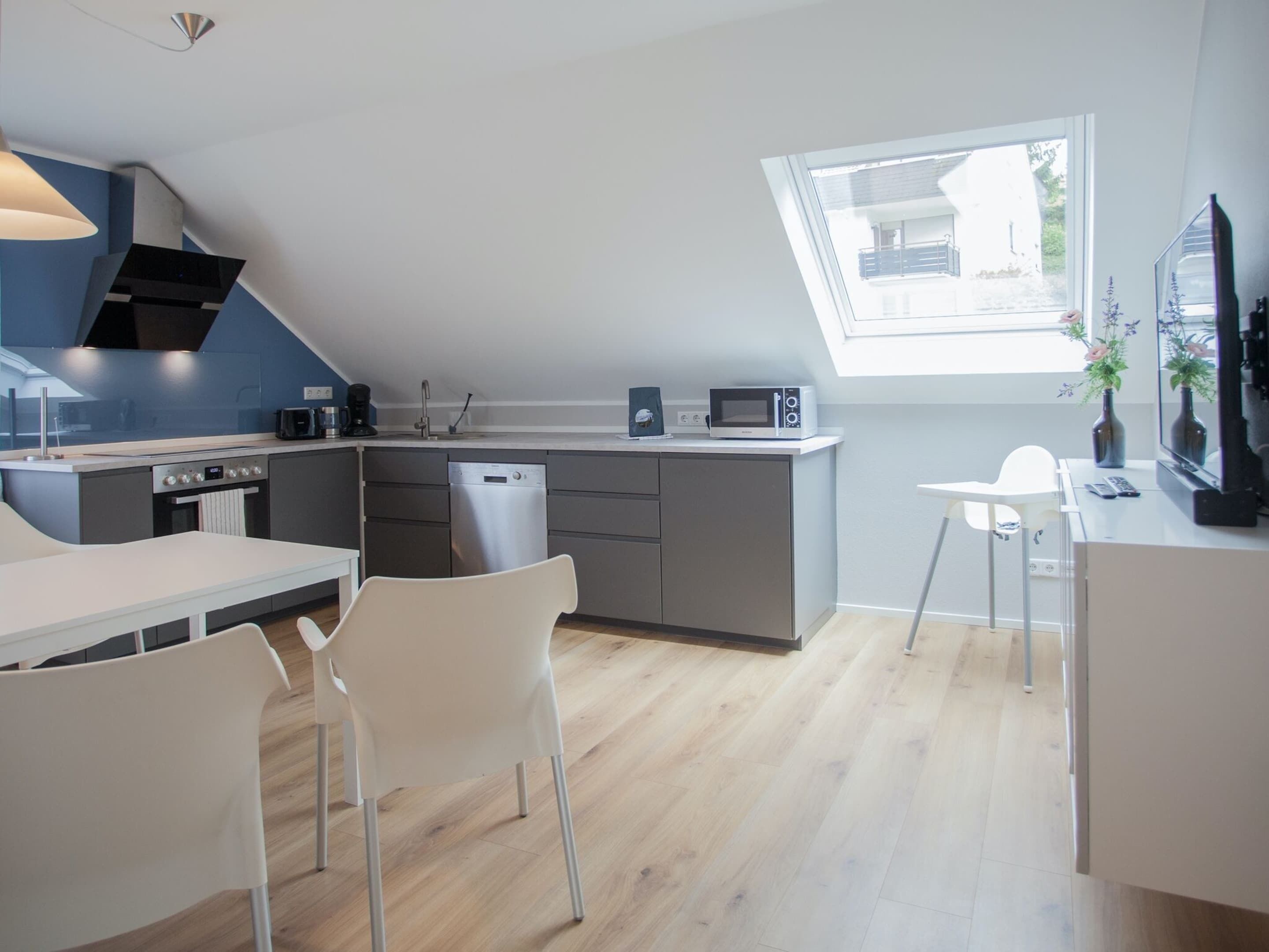 A modern kitchen with a dining area, a built-in oven, a microwave, and a dishwasher.