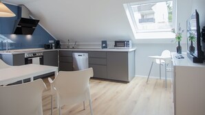 A modern kitchen with a dining area, a built-in oven, a microwave, and a dishwasher. - Chic Apartment in Niedersfeld Close to Hillebachsee (Winterberg)