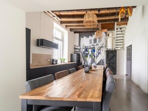 A modern kitchen with a wooden dining table, black cabinets, and a built-in stove. - Comfortable Holiday Home in Voorst in a Tranquil Location (Voorst)