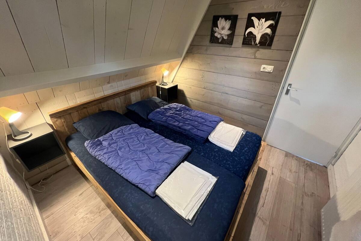 A small, cozy room with two beds, wooden walls, and a sloped ceiling.
