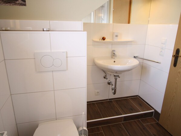 A bathroom with white tiles, a white sink, and a toilet. - Sprawling Mansion Near Ski Area in Salzburg (Eben im Pongau)