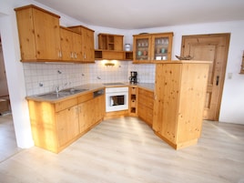 Una cocina compacta con armarios de madera, lavavajillas, horno y cafetera.