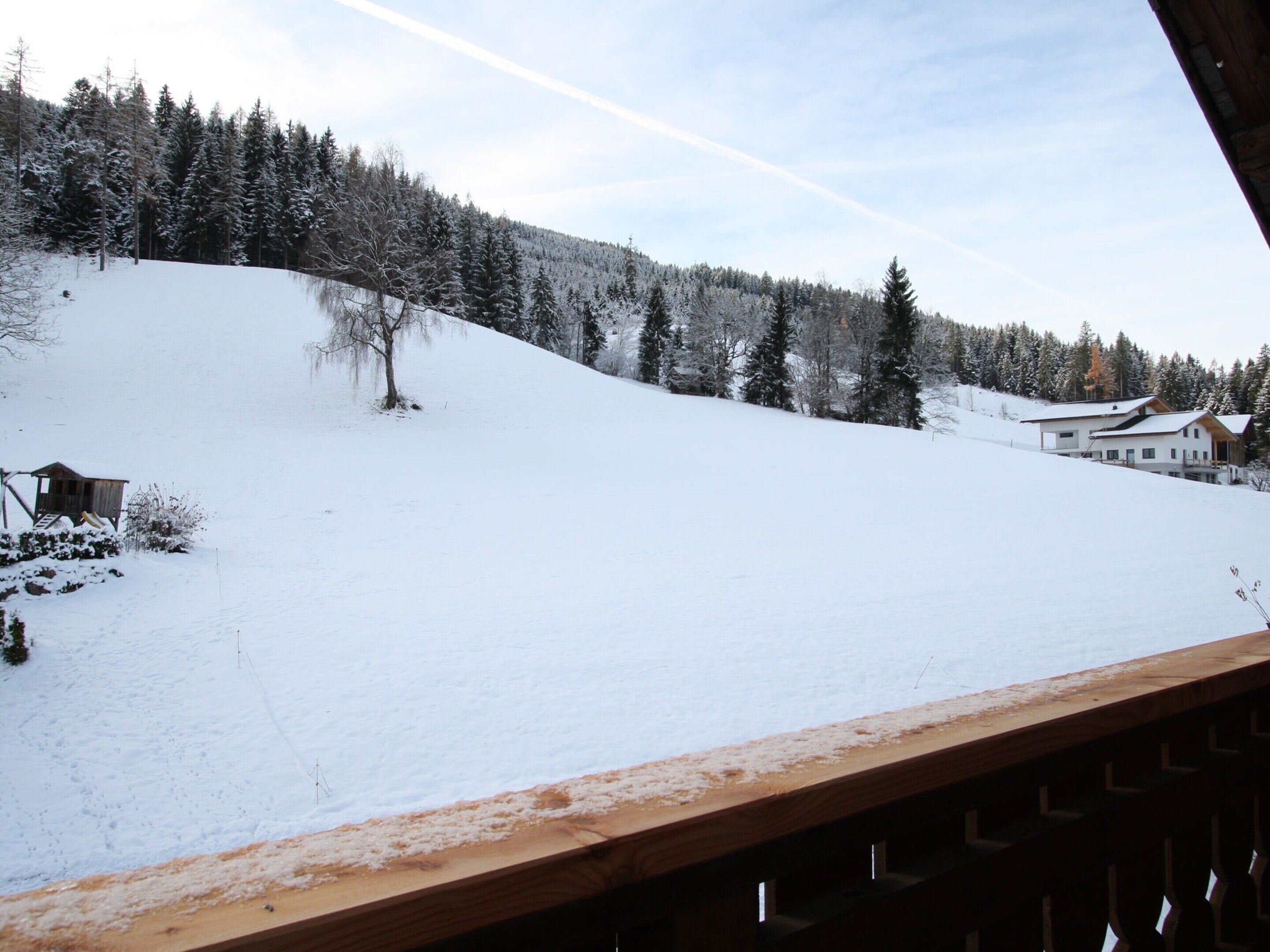 A snow-covered landscape with a wooden cabin and a modern house.