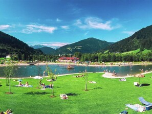 Ein Seeufer-Resort mit einem roten Gebäude, Rasenflächen und freiem Blick auf die Berge.