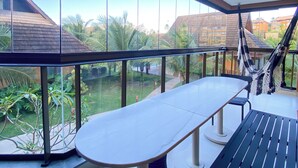 A modern outdoor dining area with a large table and benches, overlooking a garden and neighboring buildings. - Flat 15 Eco Resort Carneiros by La Playa (Tamandaré)