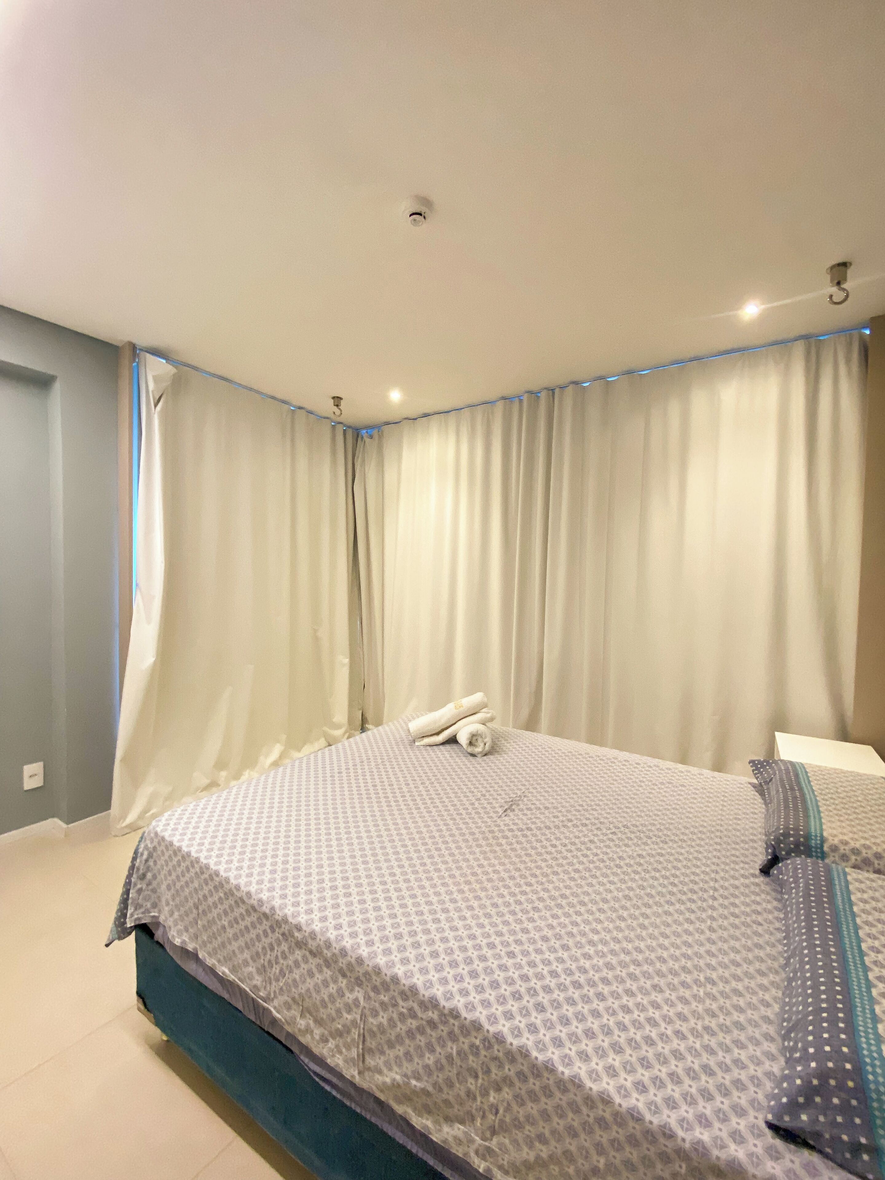 Ein Hotelzimmer mit Bett, Vorhängen und einer Deckenleuchte.