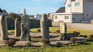 Un círculo de piedras en un área cubierta de hierba, con una casa moderna al fondo.