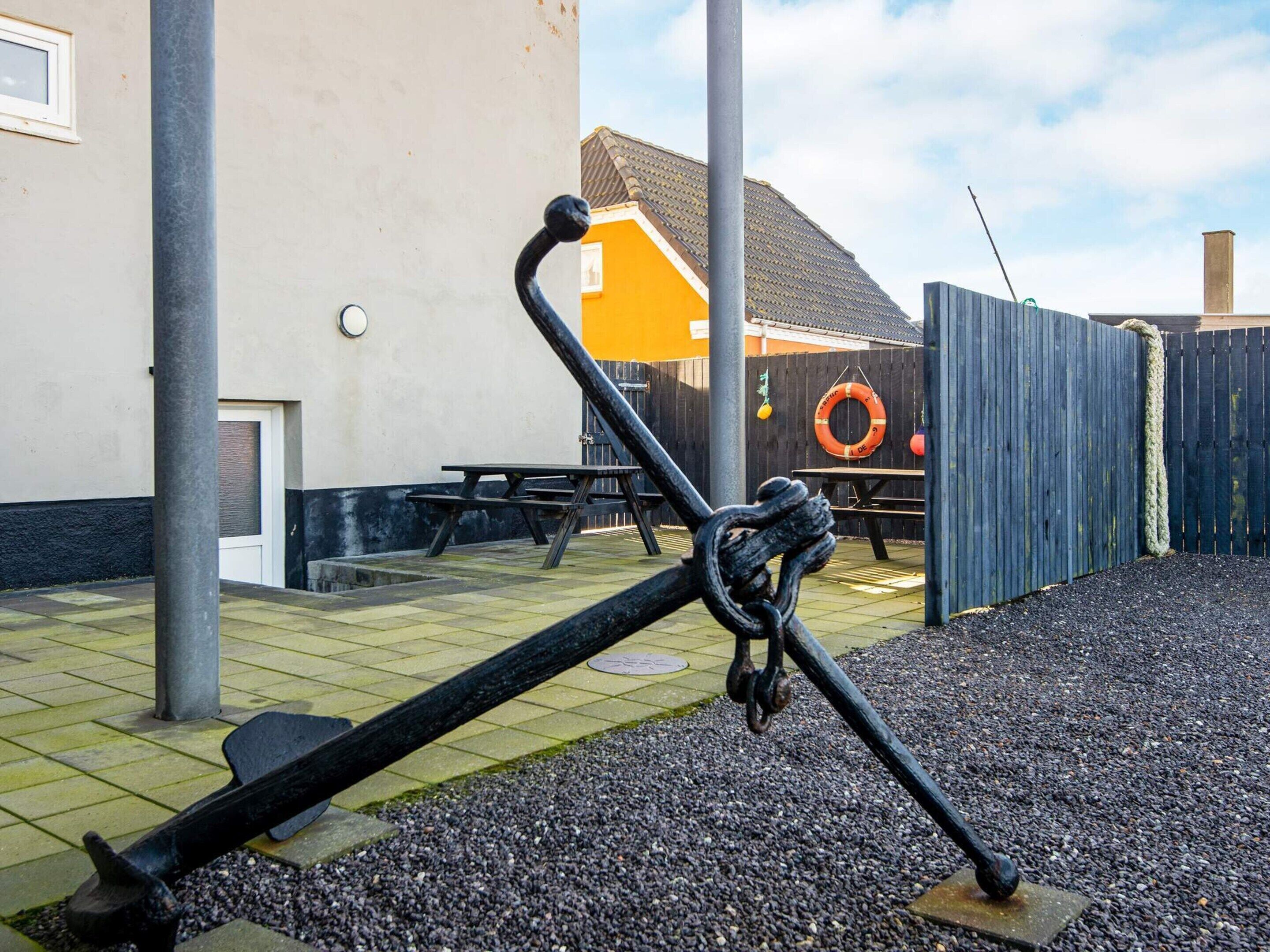 A playground with a seesaw, a wooden fence, and a building in the background.