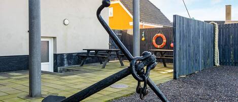 A playground with a seesaw, a wooden fence, and a building in the background.