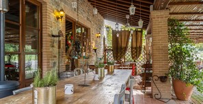 An outdoor dining area with rustic wooden tables and chairs, potted plants, and a brick wall backdrop. - Quaint Cottage in Citta Della Pieve With Pool (Citta della Pieve)
