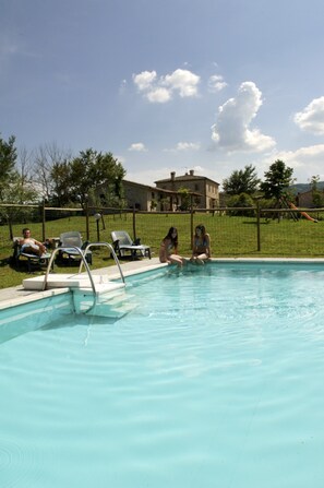 A swimming pool with lounge chairs and a house in the background. - Quaint Cottage in Citta Della Pieve With Pool (Citta della Pieve)
