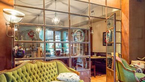 Ein Zimmer mit einem dunkelgrünen Sofa, einer Kristallleuchter und einem großen Fenster mit vielen Glasscheiben.