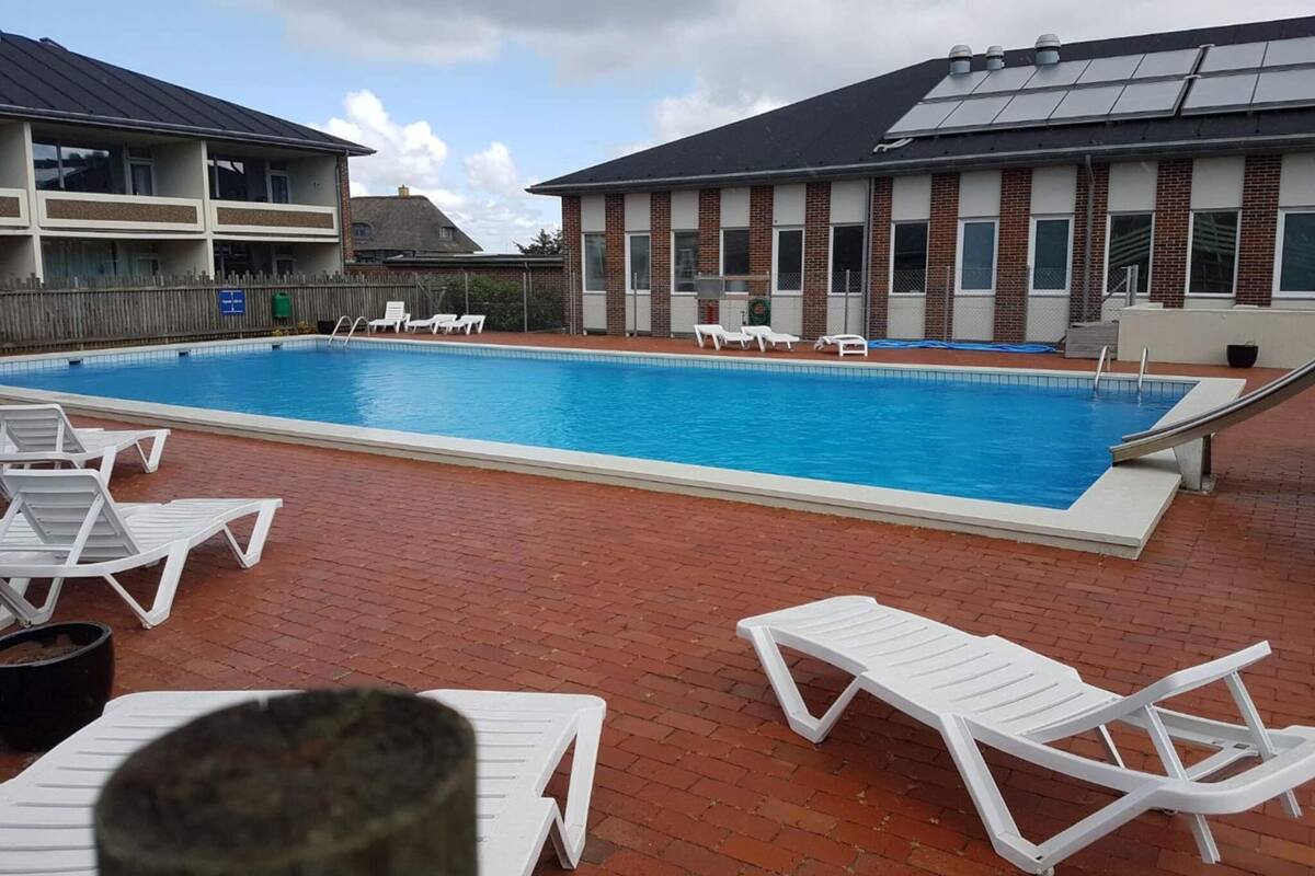 A swimming pool with lounge chairs and a building with solar panels.